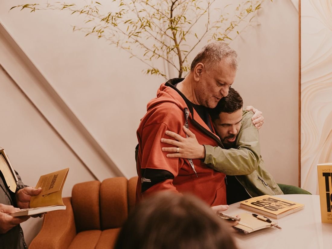 Dois homens se abraçam durante um dos encontros de lançamento do livro.