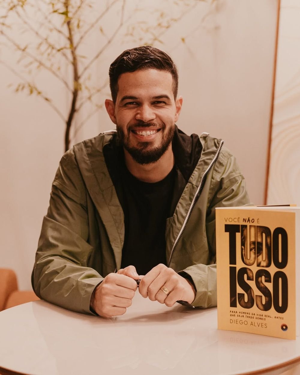 Retrato de Diego Alves sentado com o livro sobre a mesa.