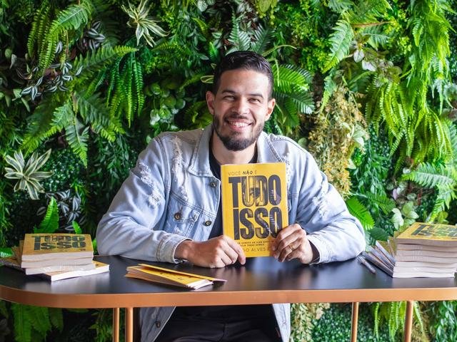 Diego Alves na mesa de autógrafos com pilhas do livro.