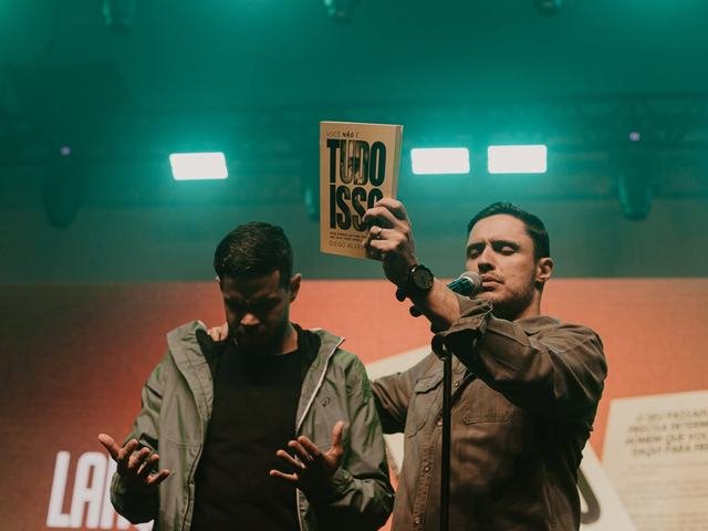 Leitor recebe o livro das mãos do autor no palco.