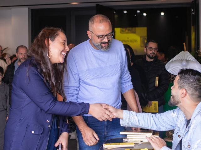 Casal cumprimenta o autor na mesa de autógrafos.