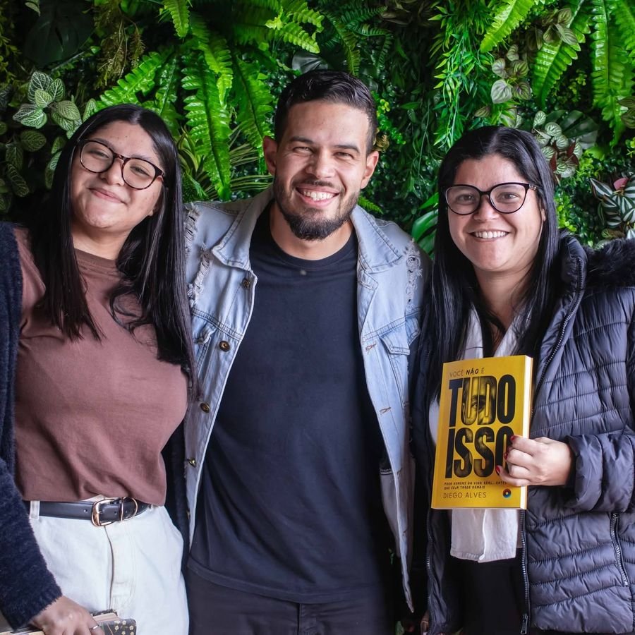 Duas leitoras ao lado de Diego Alves segurando o livro no lançamento.